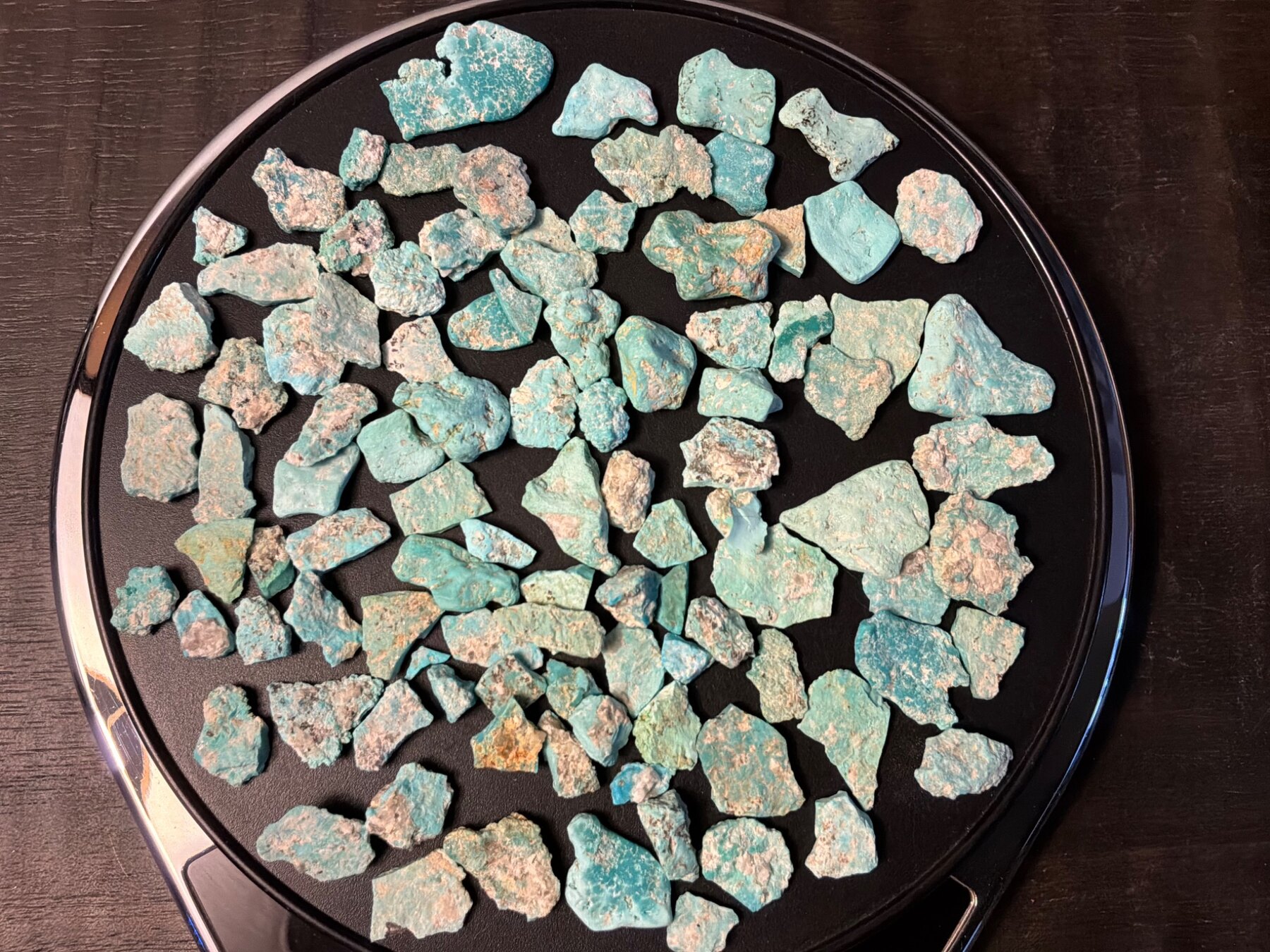 Natural blue-green Leadville turquoise rough parcel on a black background